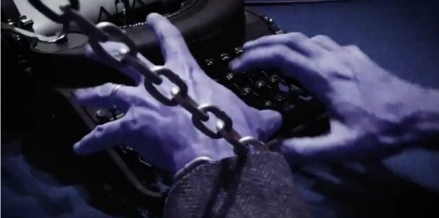 Pair of chained hands hovering over an old fashioned typewriter